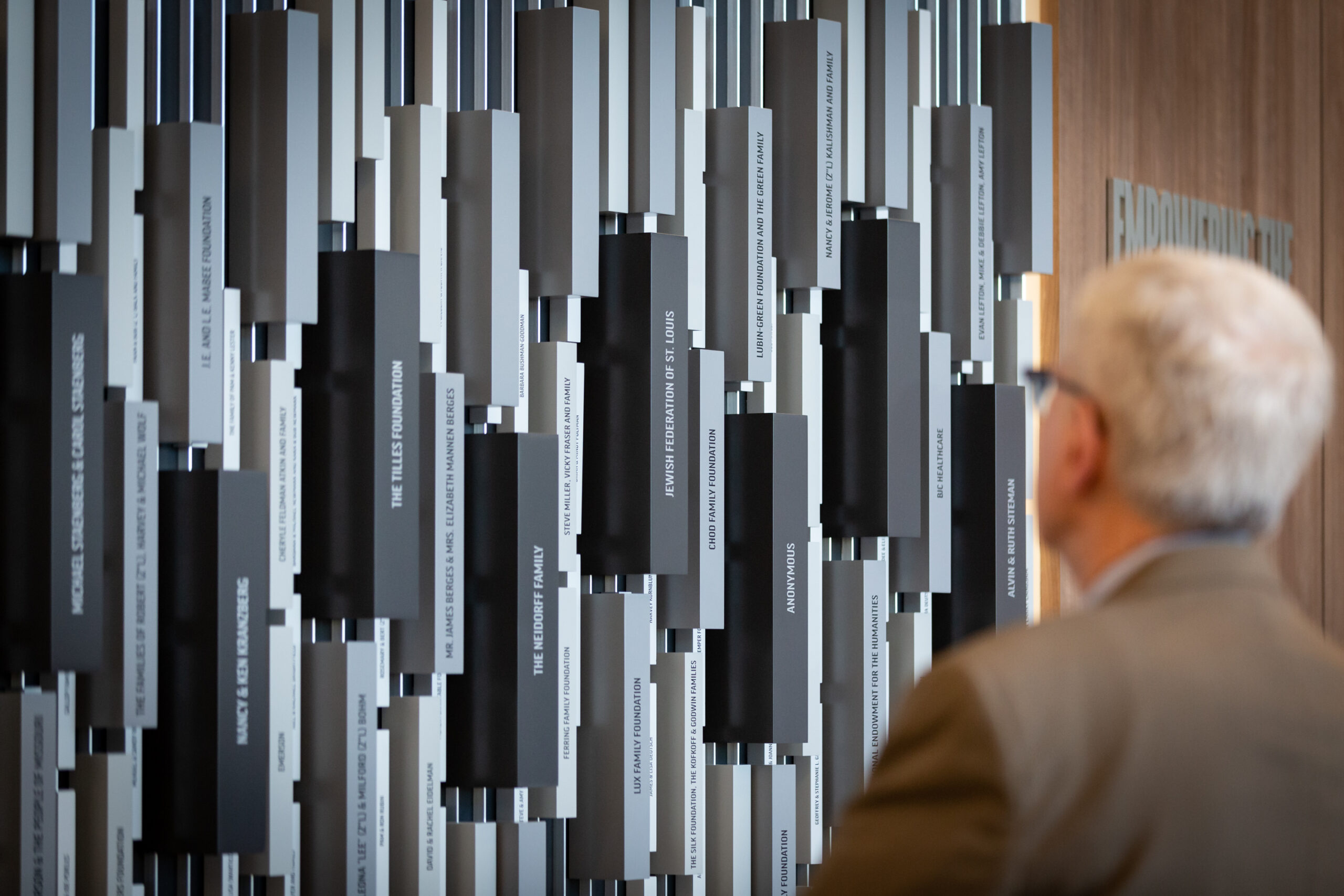 Man in suit looks at the Museum's donor wall in the Museum lobby.